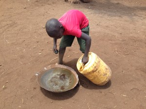 Child pouring Water from Well in larger Bowl